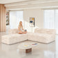 Soft sand  Modular Sectional Sofa with Asymmetrical Single Backrest  –showcased in a modern cozy living room setting. A model sits on it to demonstrate scale and comfort