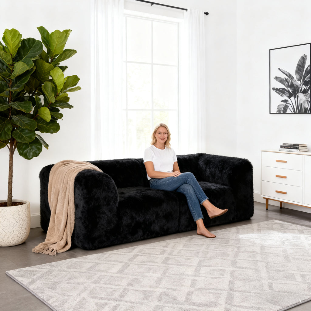 Black Modular Loveseat–showcased in a modern cozy living room setting. A model sits on it to demonstrate scale and comfort