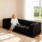 Black sofa –showcased in a modern cozy living room setting. A model sits on it to demonstrate scale and comfort